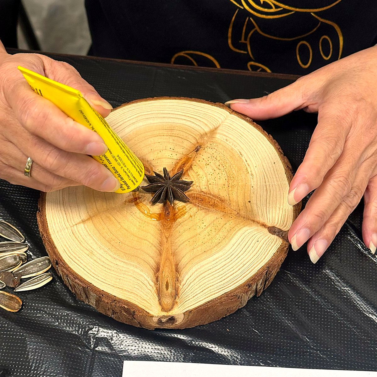 A participant's hands placing star anise at the centre of a wood round